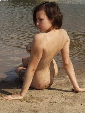 Amateur girl covers her naked body in sand while at a nude beach on dollser.com