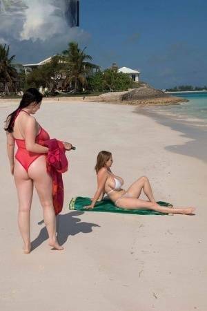 Busty lesbian girls let their huge knockers loose to kiss & lick on the beach on dollser.com