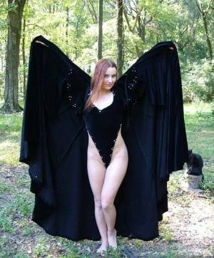 Redhead amateur Amber Lily models nude in a forest draped in a black cape on dollser.com