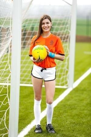 Lilly P is undressing her soccer uniform while on the field with a ball on dollser.com