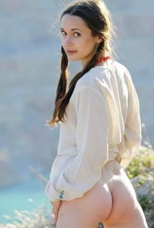 Teen model Ilona B poses nude in pigtails high above ocean waters on dollser.com