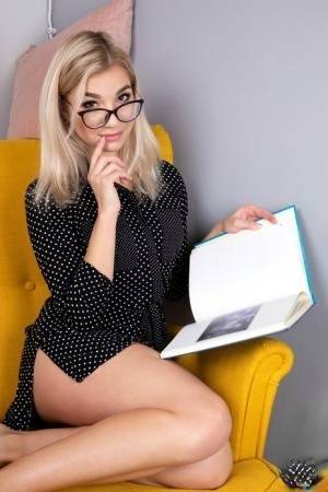 Geeky blonde Amelia undresses on a chair before playing with her shaved pussy on dollser.com