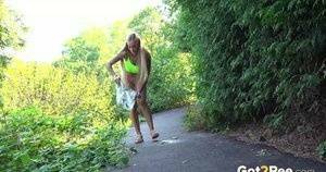 Blonde teen Daisy Lee takes a piss on a paved path through the woods on dollser.com