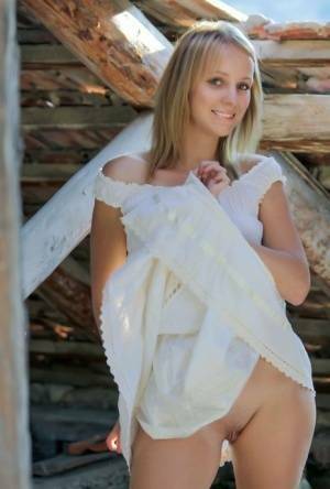 Young blonde Ilona D gets naked in a rustic setting with her boots on on dollser.com