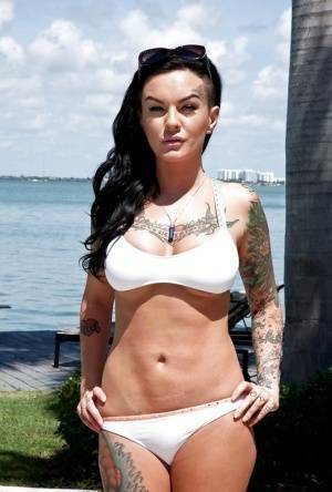 Tattooed whore Lolo Luscious exposing big hooters in swimming pool on dollser.com