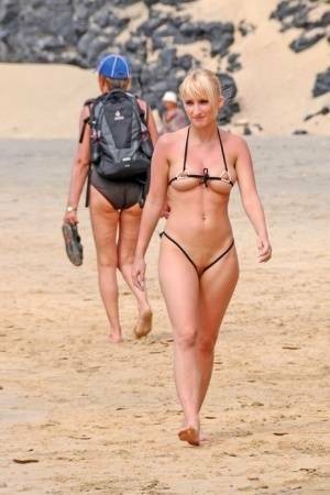 Hot blonde removes a skimpy bikini during a visit to a public beach on dollser.com